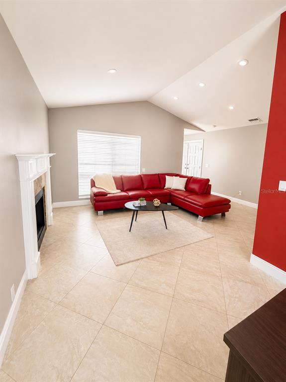 A living room features a red sectional sofa, a fireplace, and light-colored tile flooring — 17708 RIVENDEL ROAD, LUTZ, FL
