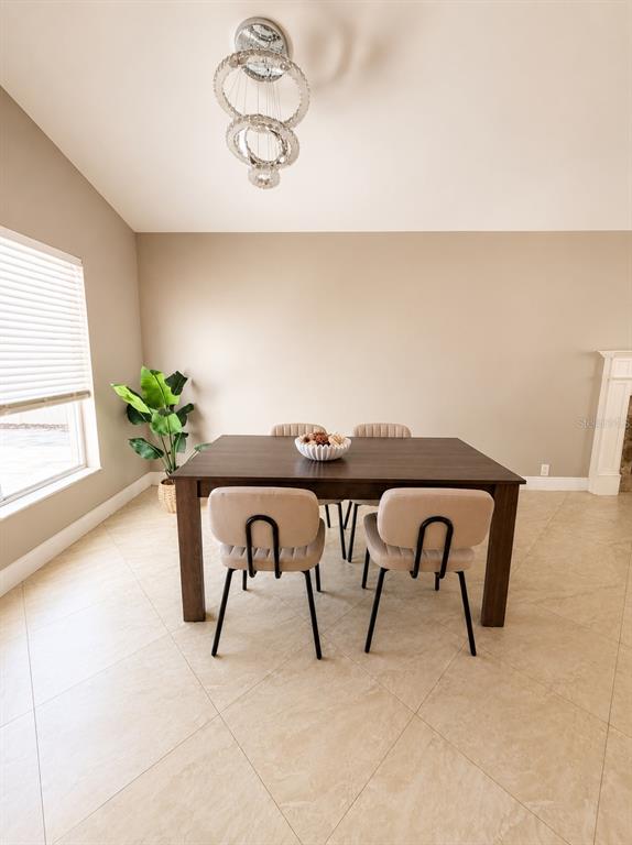A dining room features a dark wood table, four upholstered chairs, and a modern chandelier — 17708 RIVENDEL ROAD, LUTZ, FL