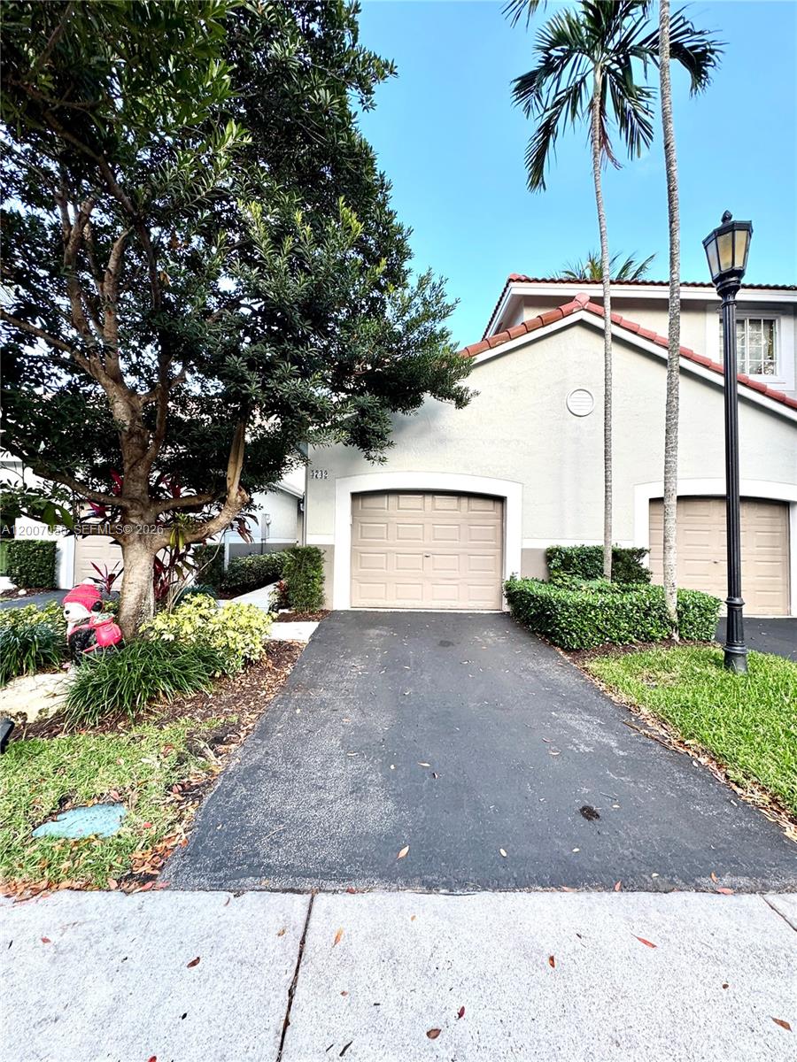 The exterior of a residential home features a paved driveway, two garage doors, and landscaping — 3742 San Simeon Cir # 3742, Weston FL 33331, WESTON, FL