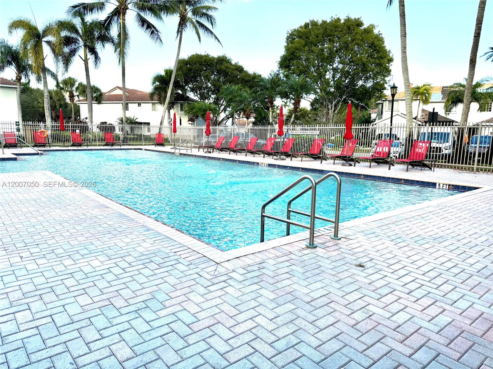 A rectangular swimming pool is surrounded by a brick patio and red lounge chairs — 3742 San Simeon Cir # 3742, Weston FL 33331, WESTON, FL