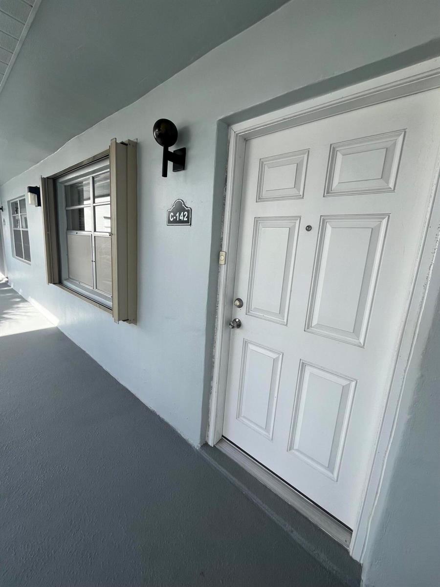 A white door with a C-142 sign and a window are on a walkway — 142 Normandy C, Delray Beach FL 33484, DELRAY BEACH, FL