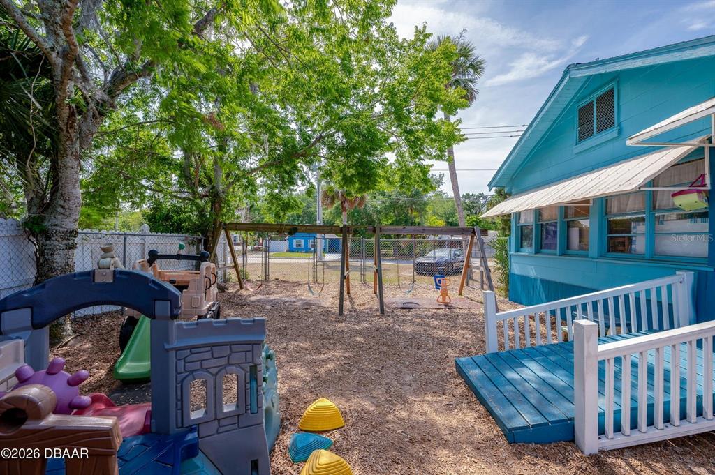 A backyard features a wooden swing set, a plastic play structure, and a blue house — 510 DUNLAWTON AVENUE, PORT ORANGE, FL