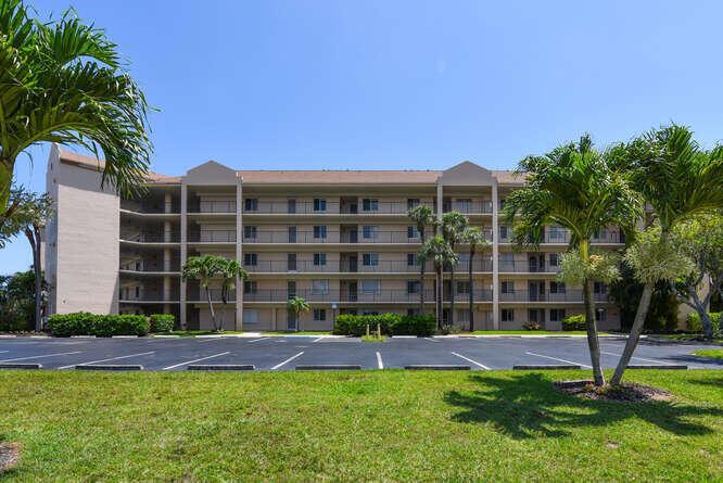 A multi-story apartment building stands behind a paved parking lot and a grassy lawn — 275 Palm Avenue # C406, Jupiter FL 33477, JUPITER, FL