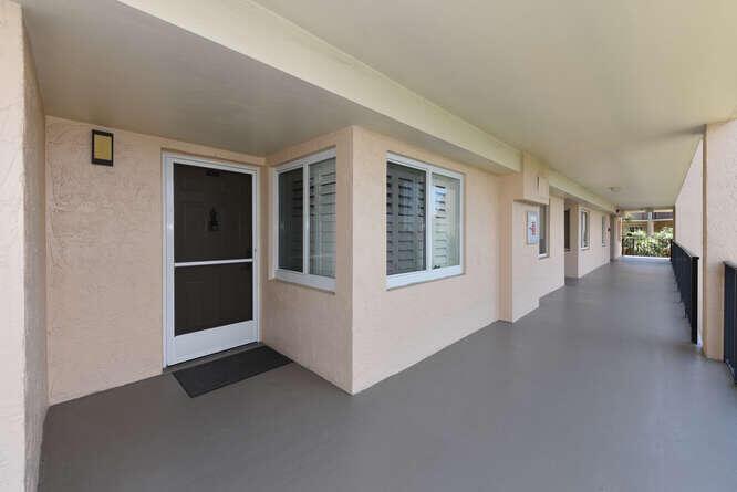 An exterior view of a covered apartment walkway with a front door and windows — 275 Palm Avenue # C406, Jupiter FL 33477, JUPITER, FL