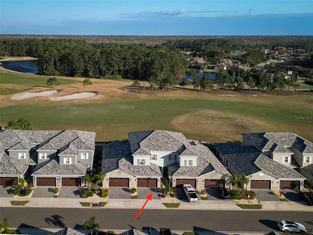 An aerial view shows a row of townhouses with garages facing a golf course — 3074 ISLES WAY, NEW SMYRNA BEACH, FL