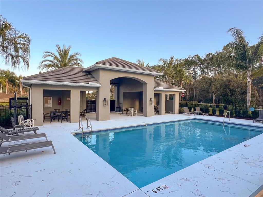 A swimming pool sits in front of a covered outdoor pavilion with lounge chairs — 3074 ISLES WAY, NEW SMYRNA BEACH, FL