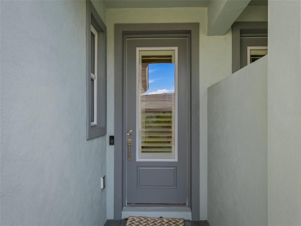 A gray front door with a glass insert is set within a light-colored entryway — 3074 ISLES WAY, NEW SMYRNA BEACH, FL