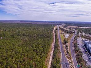 An aerial view shows a dense forest bordering a multi-lane highway and a commercial parking lot — INTERNATIONAL DRIVE, ORLANDO, FL