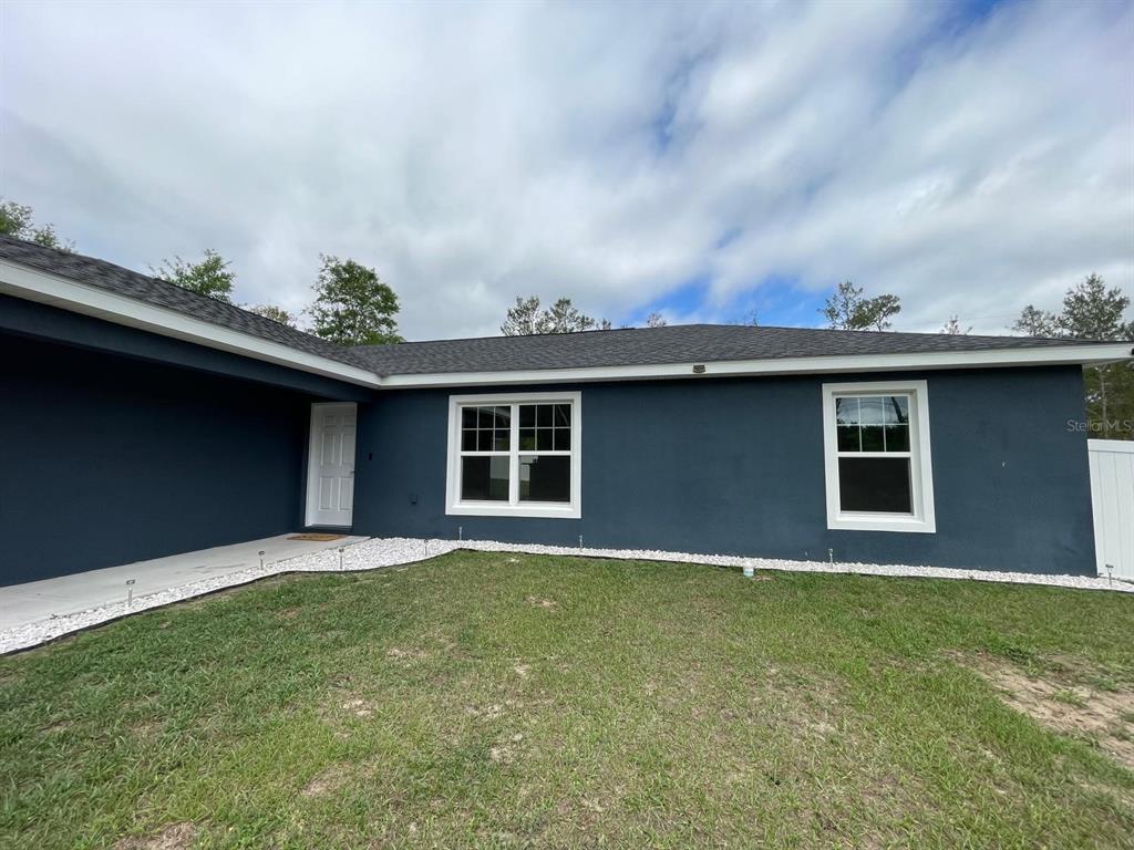 A dark blue exterior wall features two white-framed windows and a white front door — 16958 SW 20TH COURT ROAD, OCALA, FL