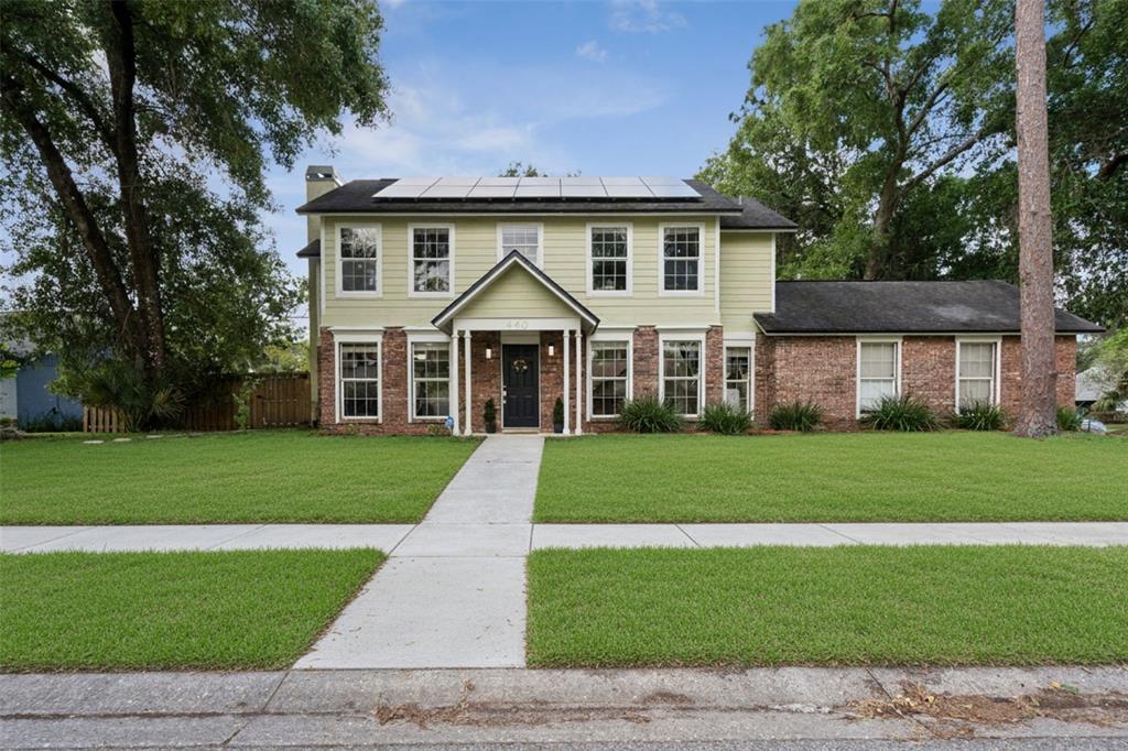 A two-story house with light green siding, brick accents, and solar panels on the roof — 440 BUCKSKIN COURT, WINTER SPRINGS, FL