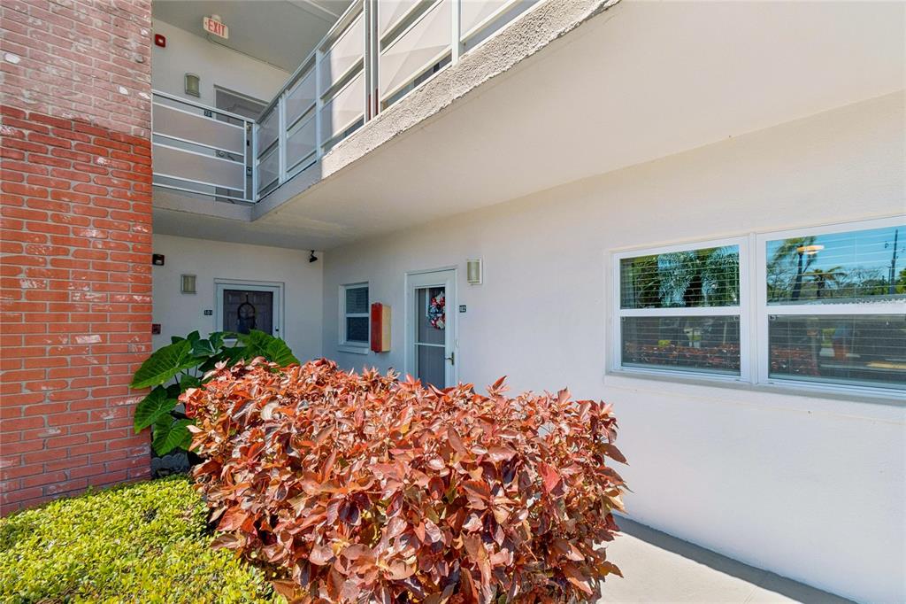 An exterior view of a multi-story apartment building with a brick facade and landscaping — 5501 80TH STREET N UNIT 102, ST PETERSBURG, FL