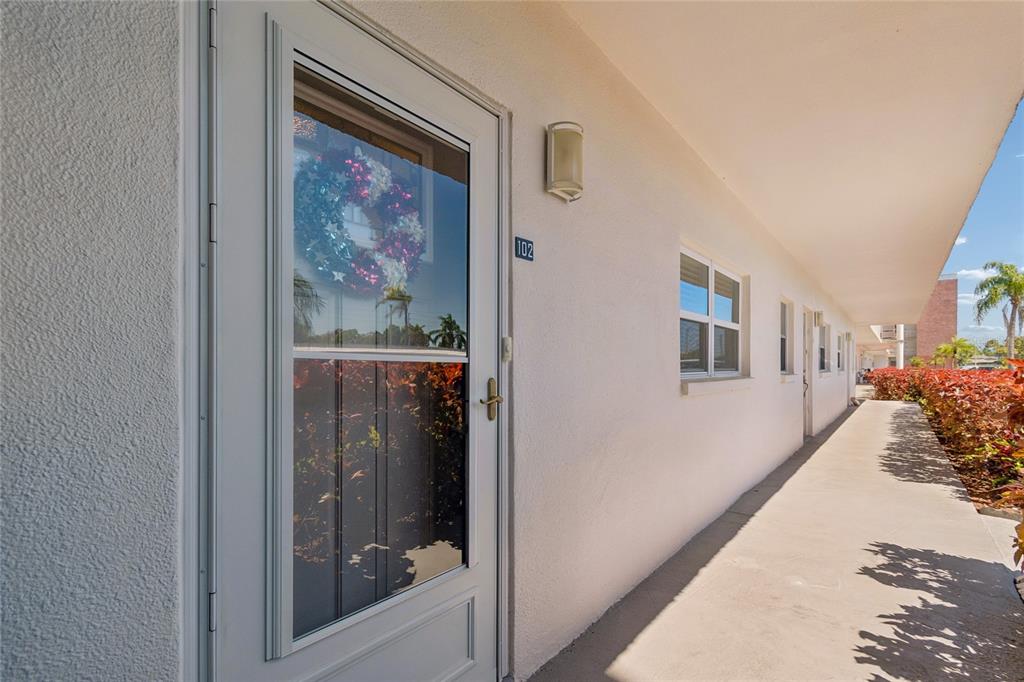 A white exterior door with a wreath and unit number 102 opens onto a walkway — 5501 80TH STREET N UNIT 102, ST PETERSBURG, FL