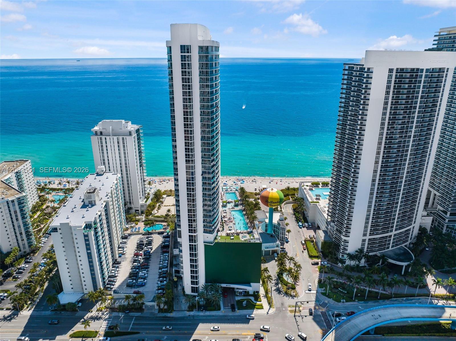 An aerial view shows high-rise residential buildings along a beach with a colorful water tower — 4111 S Ocean Dr # 2207, Hollywood FL 33019, HOLLYWOOD, FL