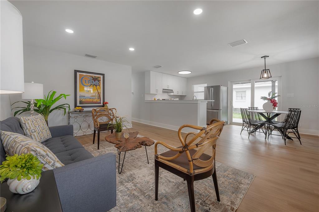 An open-concept living and dining area features light wood floors, white cabinetry, and modern furniture — 1911 W CHERRY STREET, TAMPA, FL
