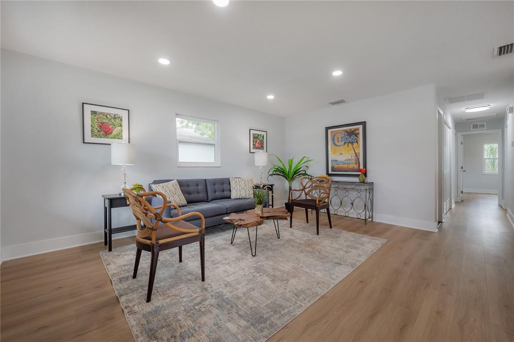 A living room features a gray sofa, two rattan chairs, and light wood-look flooring — 1911 W CHERRY STREET, TAMPA, FL