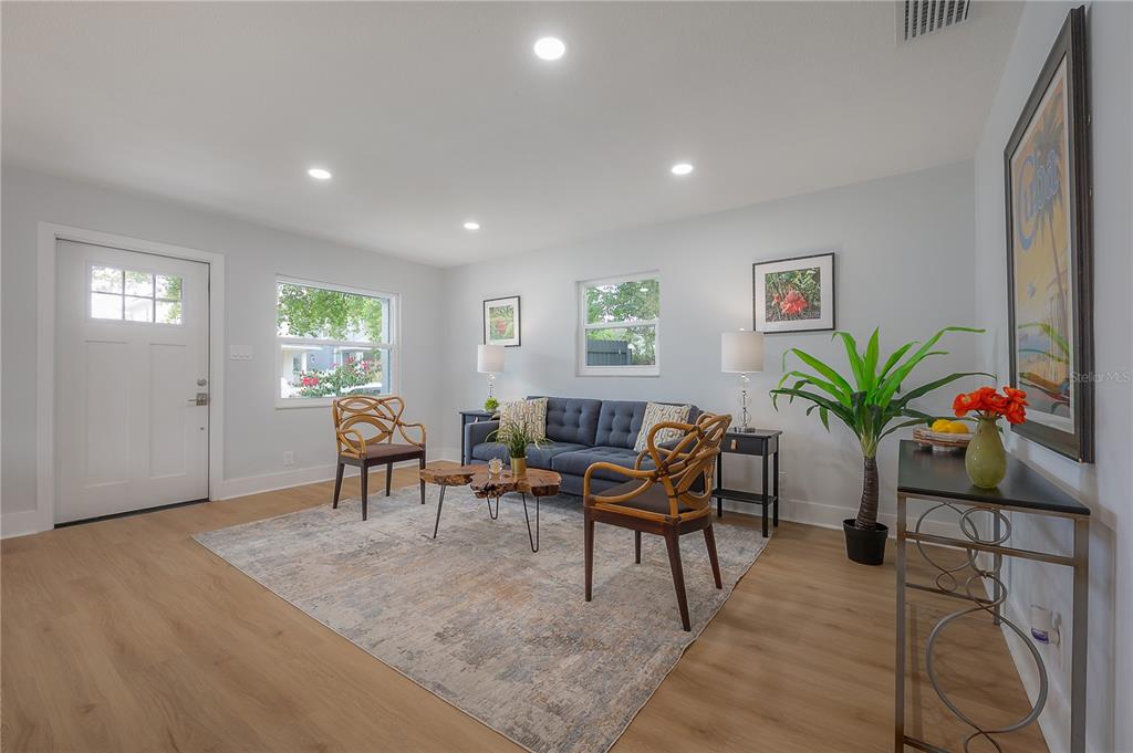 A living room features light wood floors, a blue sofa, and two rattan accent chairs — 1911 W CHERRY STREET, TAMPA, FL