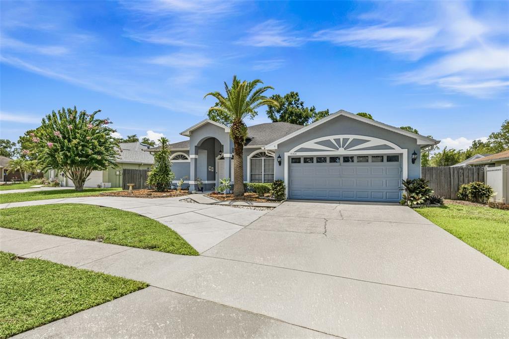 A single-story house with a gray exterior, a two-car garage, and a palm tree — 15306 CARROLLTON LANE, TAMPA, FL