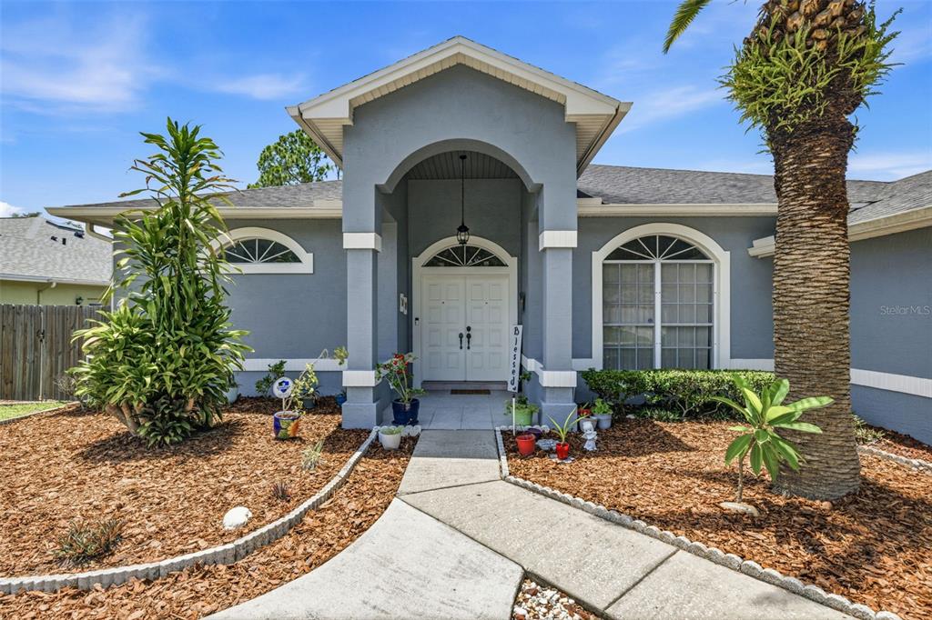 The exterior of a gray house features a covered entryway with a double door — 15306 CARROLLTON LANE, TAMPA, FL