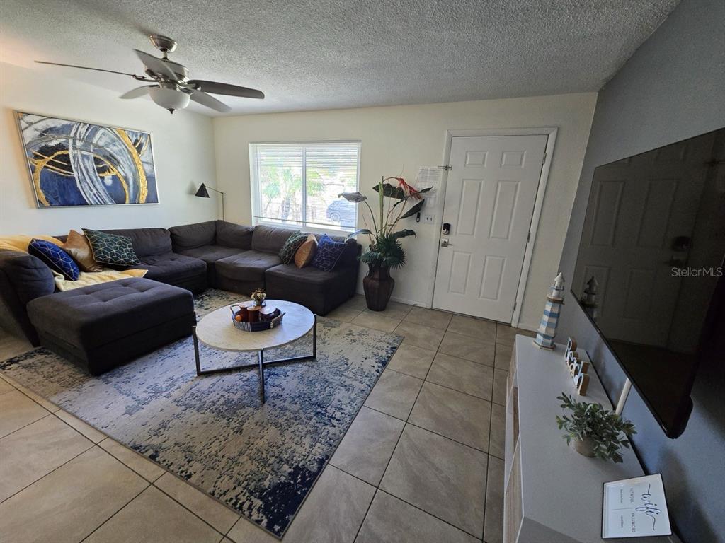 A living room features a large sectional sofa, a round coffee table, and a television — 1430 PARKVIEW LANE, LARGO, FL