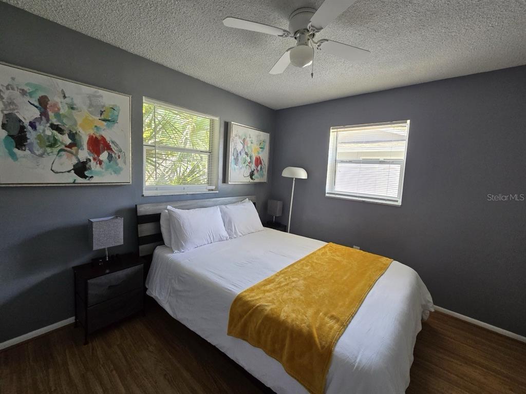 A bedroom features gray walls, a bed with a yellow throw, and two windows — 1430 PARKVIEW LANE, LARGO, FL