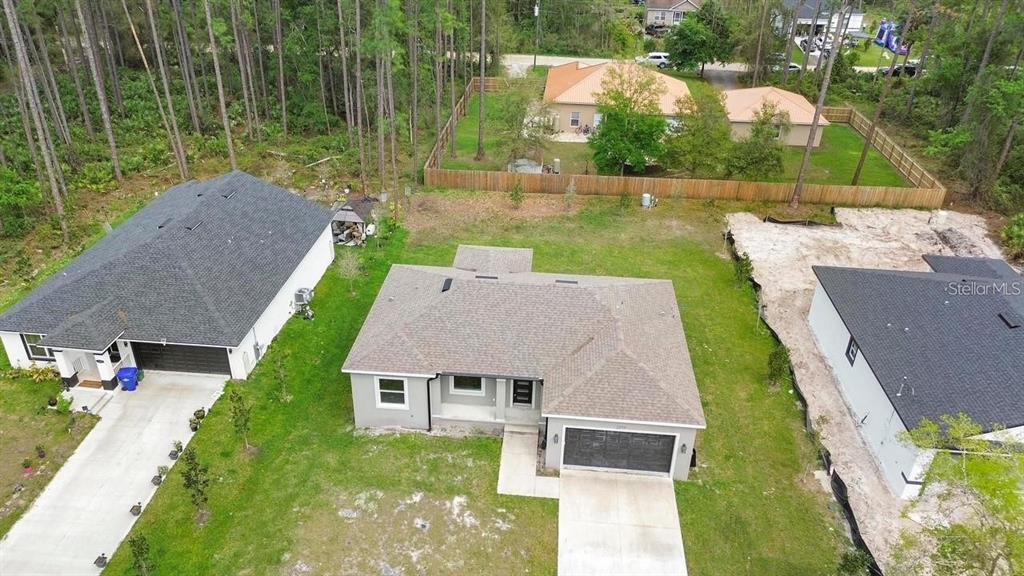 An aerial view shows three suburban houses with driveways and lawns surrounded by wooded areas — 2379 8TH AVENUE, DELAND, FL
