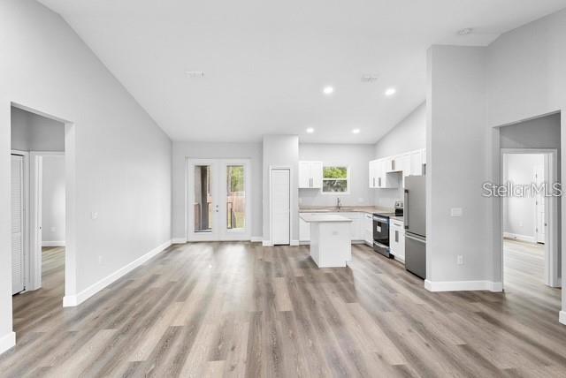 A bright, open-concept kitchen and living area features white cabinetry, a center island, and wood-look flooring — 2379 8TH AVENUE, DELAND, FL