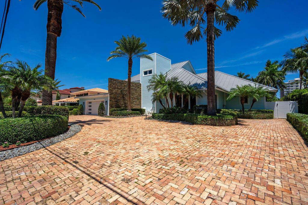 A brick driveway leads to a light blue house with a stone accent wall and palms — 4130 NE 31st Avenue, Lighthouse Point FL 33064, LIGHTHOUSE POINT, FL