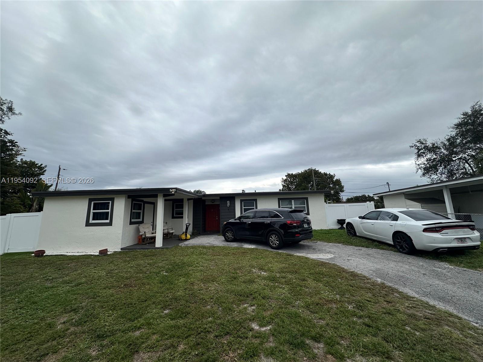 A single-story house with a white exterior, dark trim, and a driveway with two cars — 5700 SW 54th Ter, Davie FL 33314, DAVIE, FL