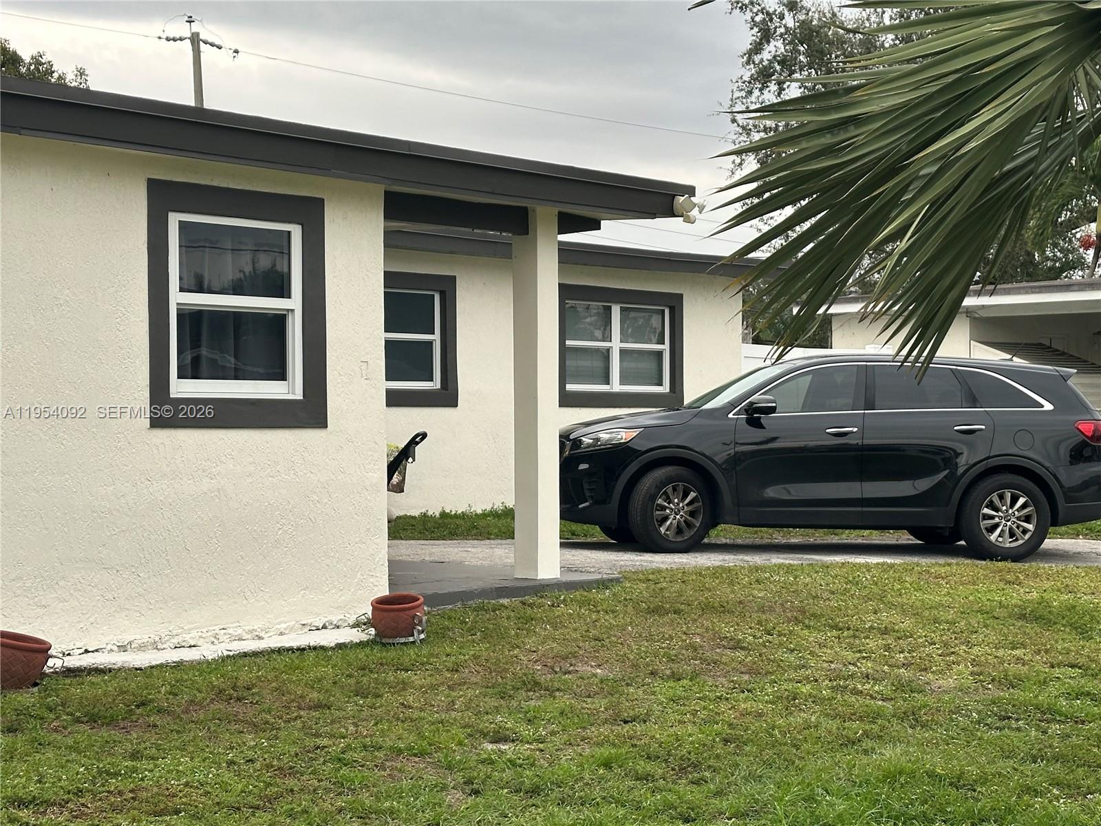 A single-story house with a white stucco exterior, dark trim, and a parked black SUV — 5700 SW 54th Ter, Davie FL 33314, DAVIE, FL