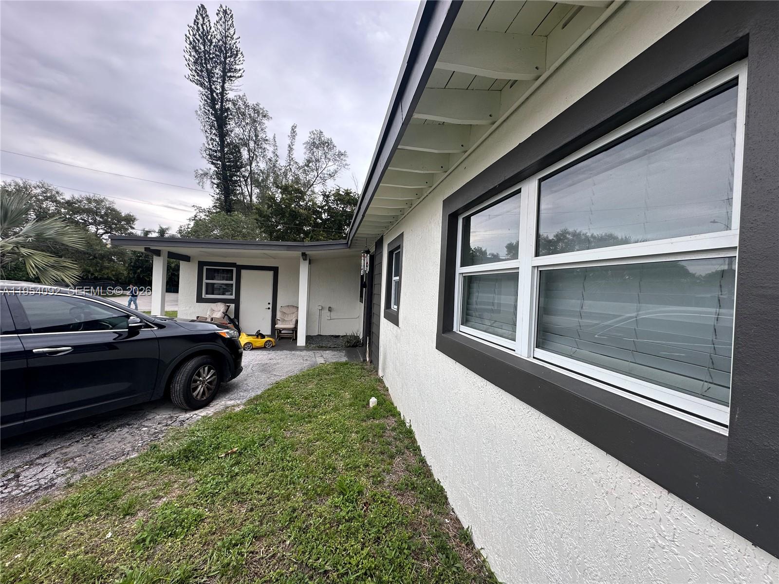 A black car is parked on a driveway next to a white house with dark trim — 5700 SW 54th Ter, Davie FL 33314, DAVIE, FL