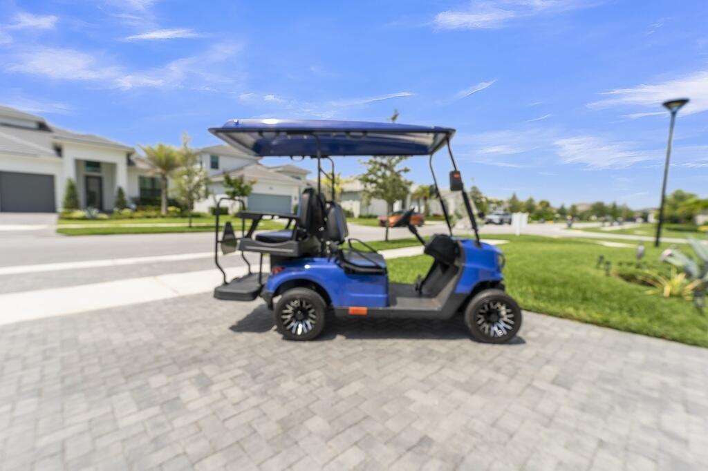 A blue golf cart is parked on a paved driveway in front of a suburban house — 15665 Merritt Drive, Westlake FL 33470, WESTLAKE, FL