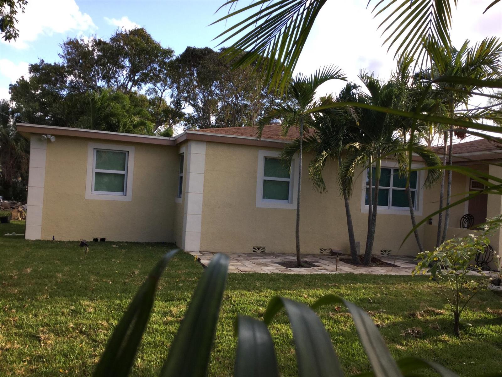 A light yellow house exterior with white trim, palm trees, and a stone patio — 130 NW 5th Avenue, Boynton Beach FL 33435, BOYNTON BEACH, FL