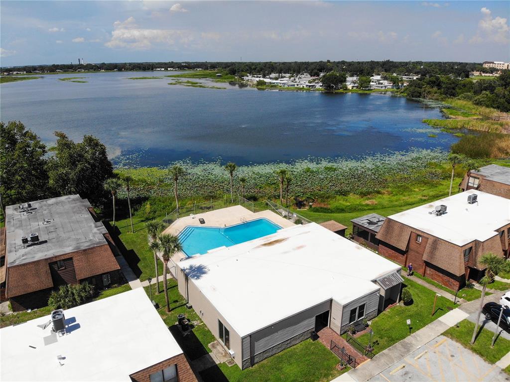 An aerial view shows a swimming pool situated between apartment buildings near a large lake — 1836 N CRYSTAL LAKE DRIVE UNIT 95, LAKELAND, FL