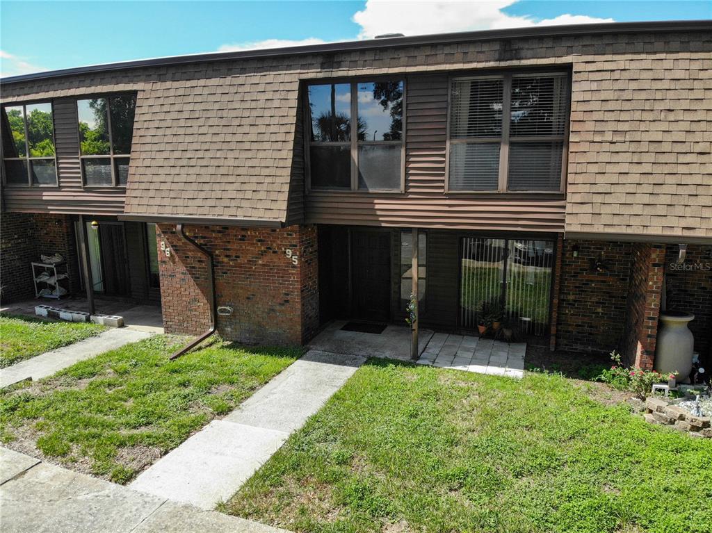 A two-story townhouse exterior features brown shingle siding, brick accents, and a concrete walkway — 1836 N CRYSTAL LAKE DRIVE UNIT 95, LAKELAND, FL