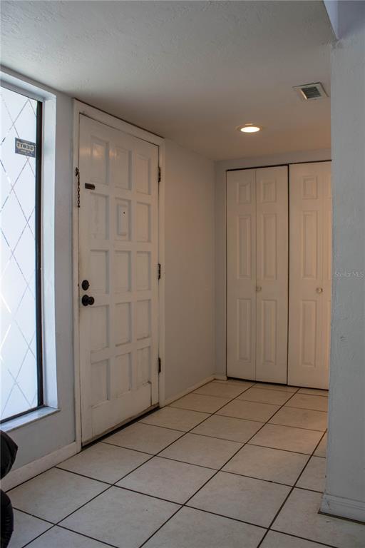 An entryway features a white paneled door, tiled flooring, and a double-door closet — 1836 N CRYSTAL LAKE DRIVE UNIT 95, LAKELAND, FL