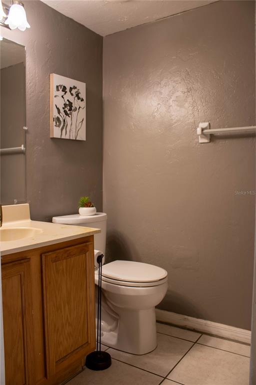 A bathroom features a wooden vanity, a white toilet, and gray walls with floral art — 1836 N CRYSTAL LAKE DRIVE UNIT 95, LAKELAND, FL