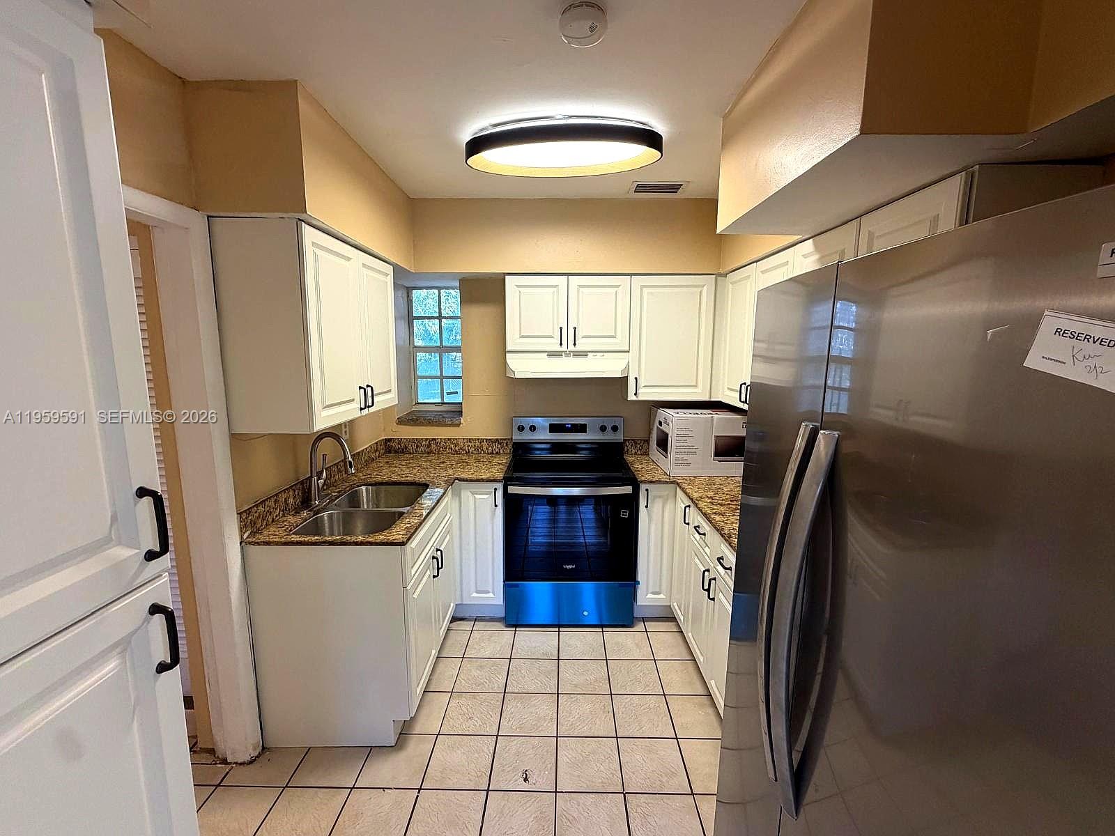 A kitchen features white cabinets, granite countertops, stainless steel appliances, and tiled flooring — 14407 NE 5th Ave # 14407, Miami FL 33161, MIAMI, FL