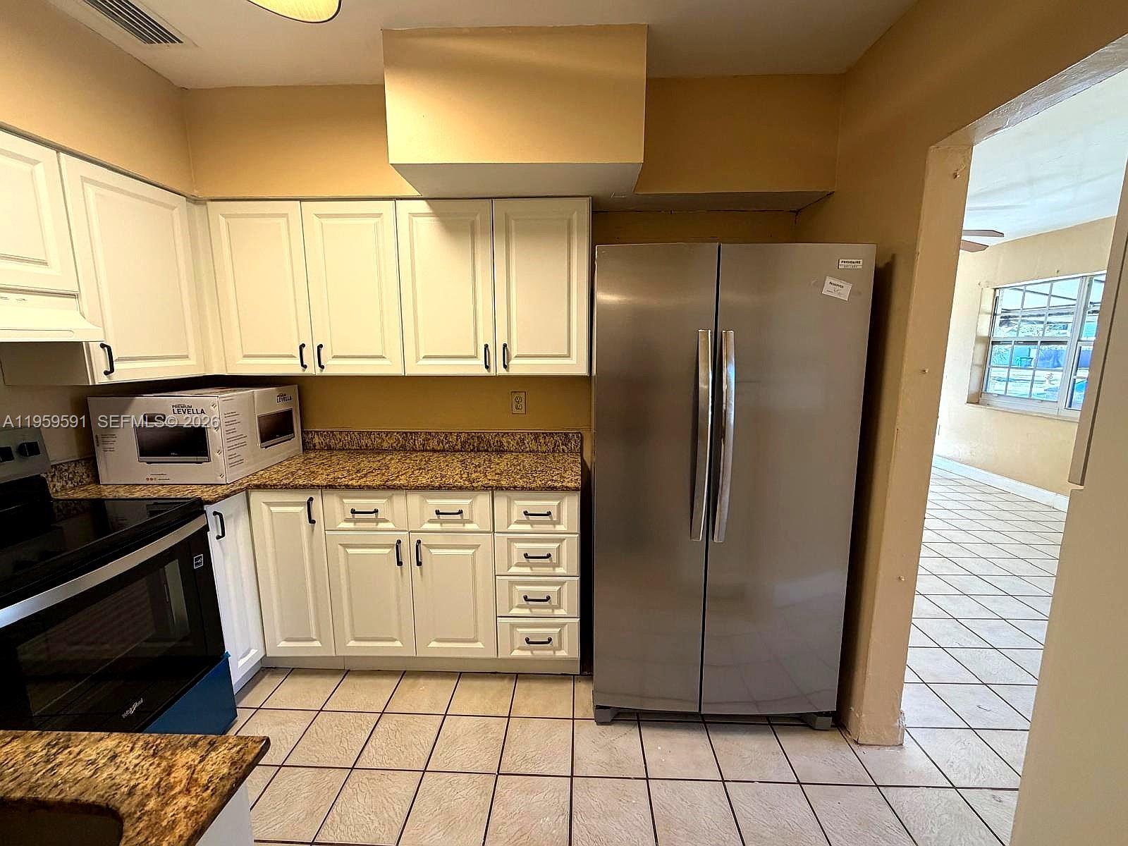 A kitchen features white cabinets, granite countertops, stainless steel appliances, and beige tile flooring — 14407 NE 5th Ave # 14407, Miami FL 33161, MIAMI, FL