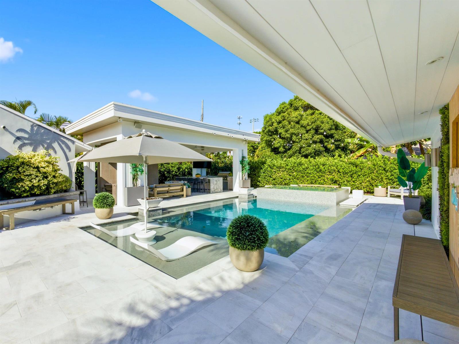 A modern backyard features a swimming pool with a tanning ledge, umbrella, and covered patio — 2210 NE 3rd Ave Avenue, Delray Beach FL 33444, DELRAY BEACH, FL