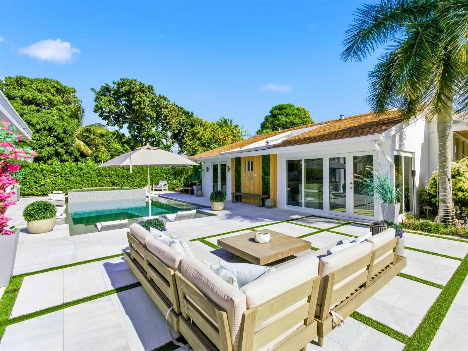 A backyard patio features a swimming pool, lounge seating, and a white house exterior — 2210 NE 3rd Ave Avenue, Delray Beach FL 33444, DELRAY BEACH, FL