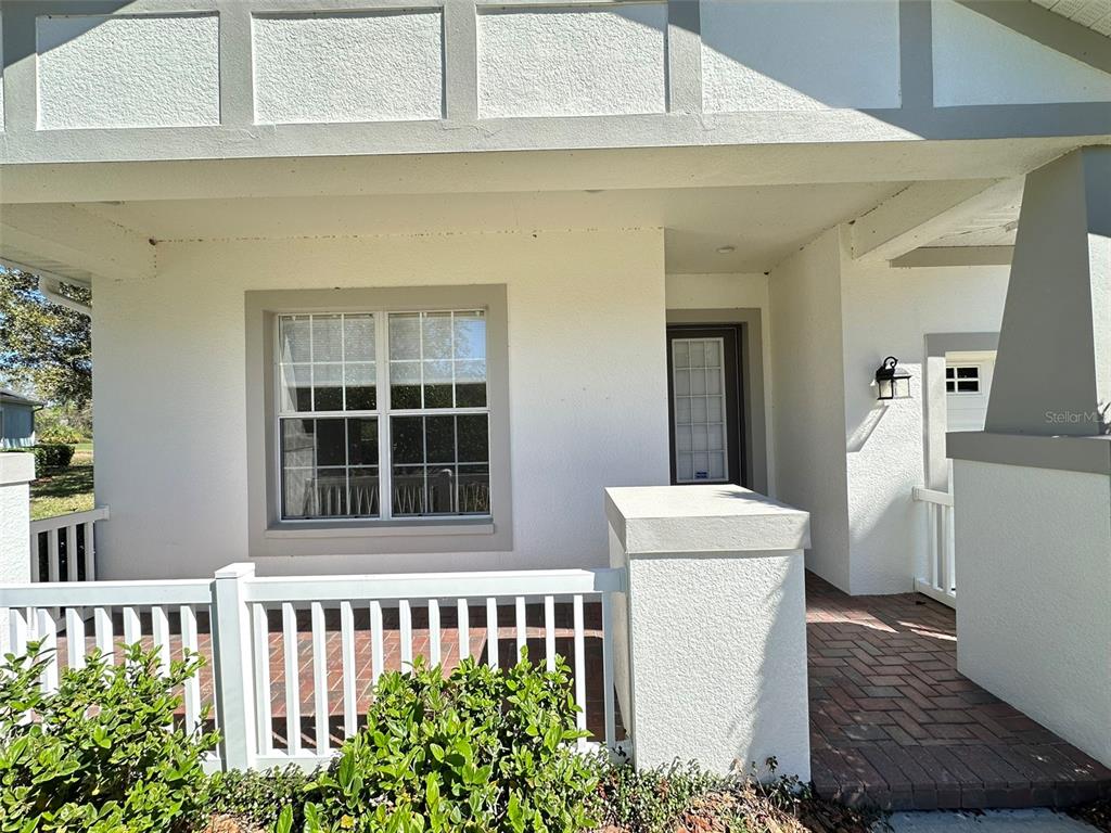 A white house exterior features a covered porch, a brick walkway, and a large window — 8120 TURKEY HILL COURT, TAMPA, FL