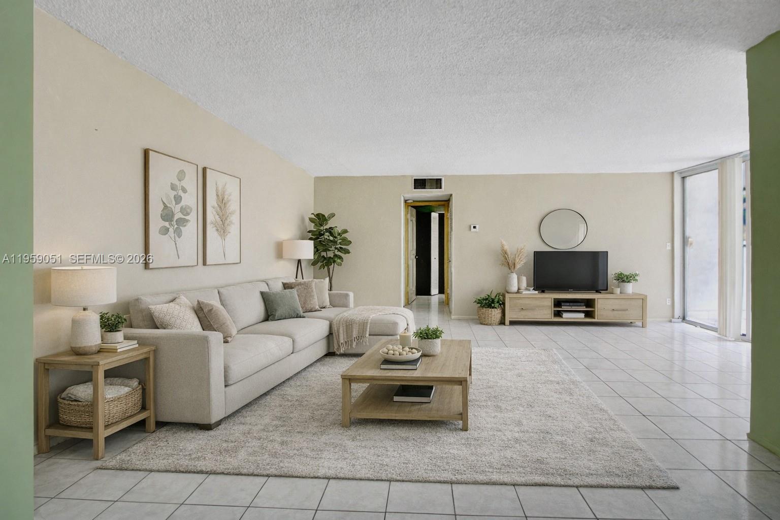 A living room features a beige sectional sofa, a wooden coffee table, and tile flooring — 942 NE 199th St # 2F, Miami FL 33179, MIAMI, FL