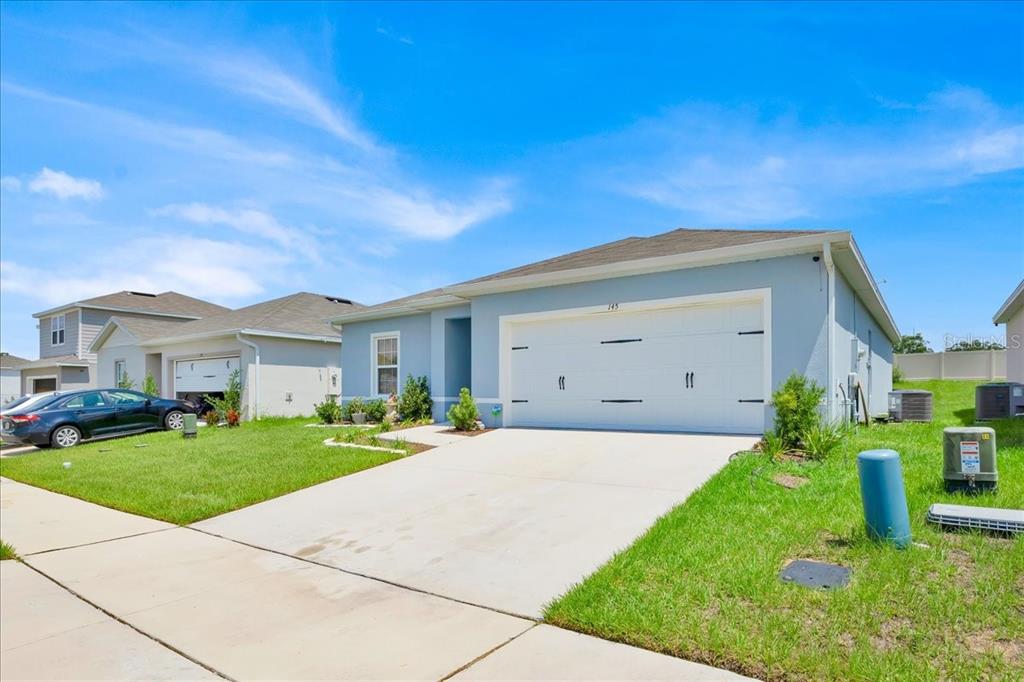A light blue single-story house with a two-car garage and a concrete driveway — 145 PIAVE STREET, HAINES CITY, FL