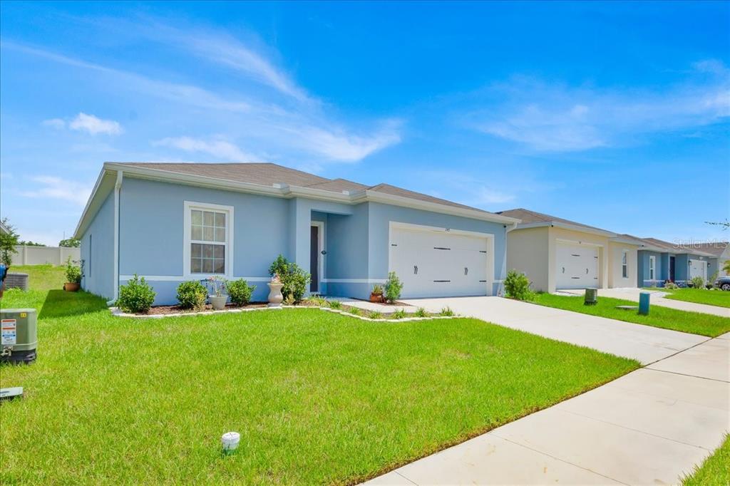 A light blue single-story suburban house with a two-car garage and a front lawn — 145 PIAVE STREET, HAINES CITY, FL