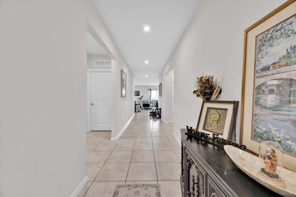 A long hallway with light tile flooring leads from a foyer into a living area — 145 PIAVE STREET, HAINES CITY, FL