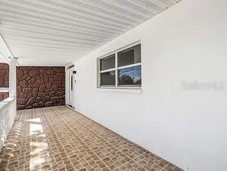 A covered porch features a tiled floor, a white wall with a window, and stone-textured siding — 5910 DENVER STREET NE, ST PETERSBURG, FL