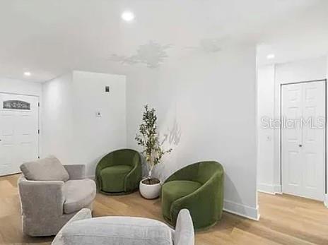 A bright room features light wood flooring, two green armchairs, and two gray armchairs — 5910 DENVER STREET NE, ST PETERSBURG, FL
