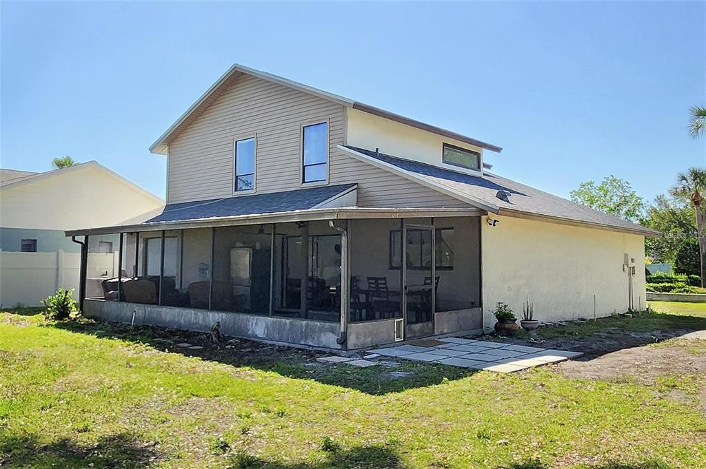 A two-story house with beige siding and a large screened-in patio in the backyard — 16169 GARDENDALE DRIVE, TAMPA, FL