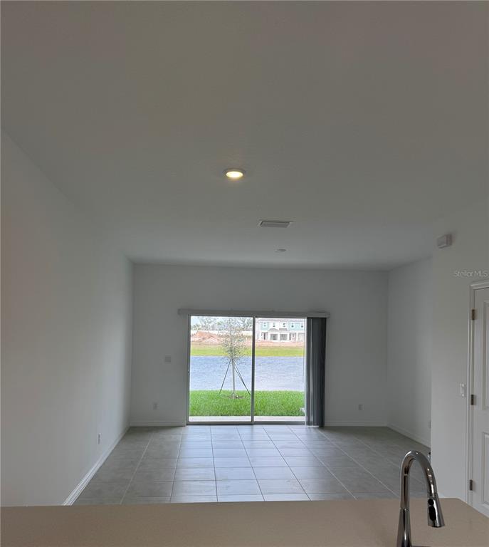 An interior view of a room with tile flooring, a sliding glass door, and water view — 16559 SAN NICOLA PLACE, BRADENTON, FL
