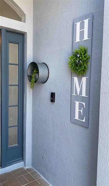 A gray front door next to a wall with a vertical "HOME" sign and planter — 943 CORVINA DRIVE, DAVENPORT, FL